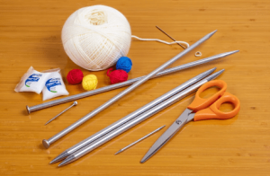 Nguyên liệu đầy đủ cho móc khóa cục bông: len pastel, kim móc, bông nhồi, charm và phụ kiện đi kèm.